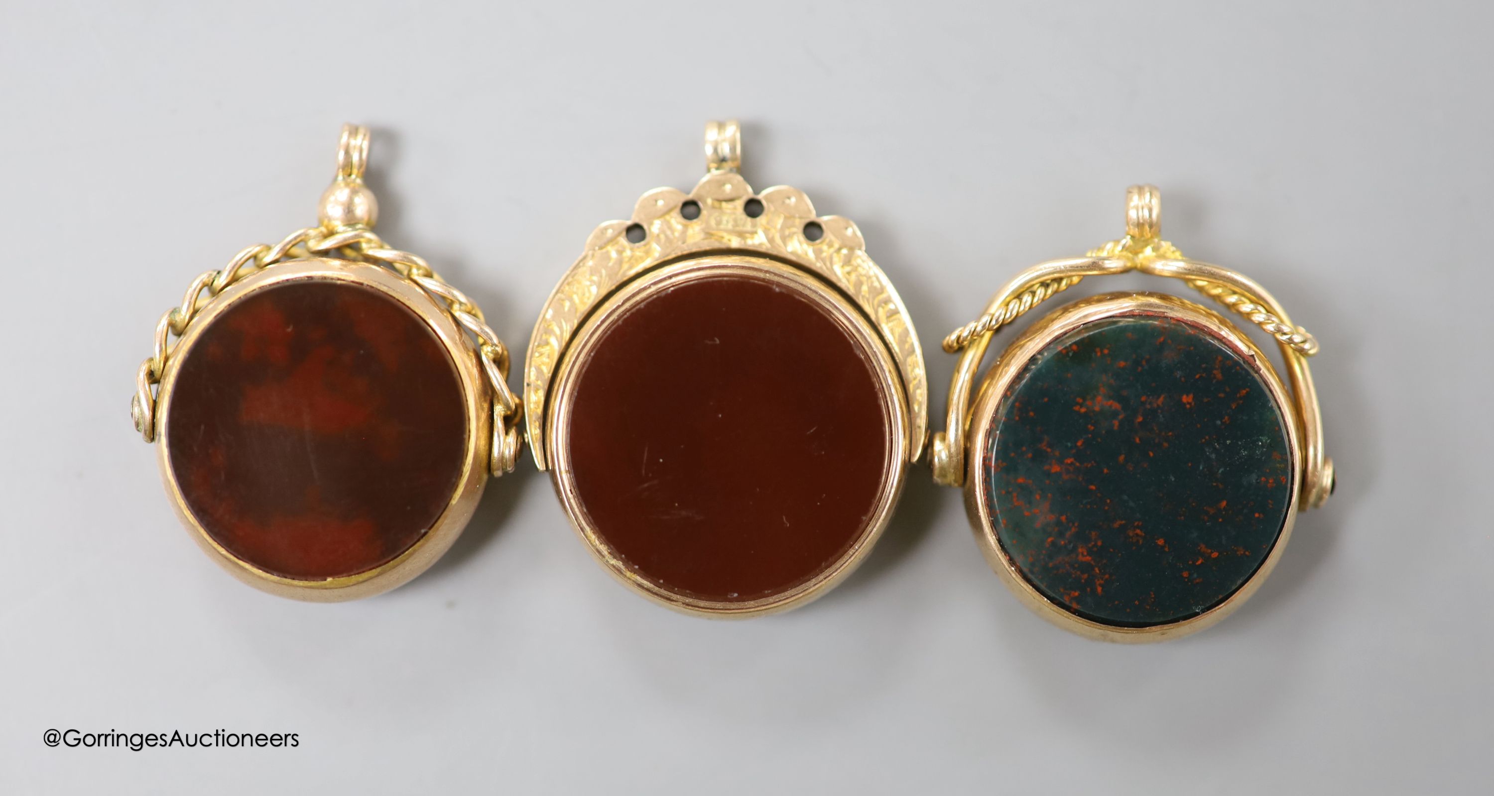 Three assorted late 19th/early 20th century 9ct mounted bloodstone and carnelian set swivelling fob seals, largest overall 29mm, gross weight, 19.7 grams.